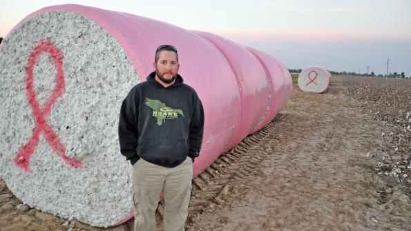 Jason Chandler with round cotton bales in pink plastic
